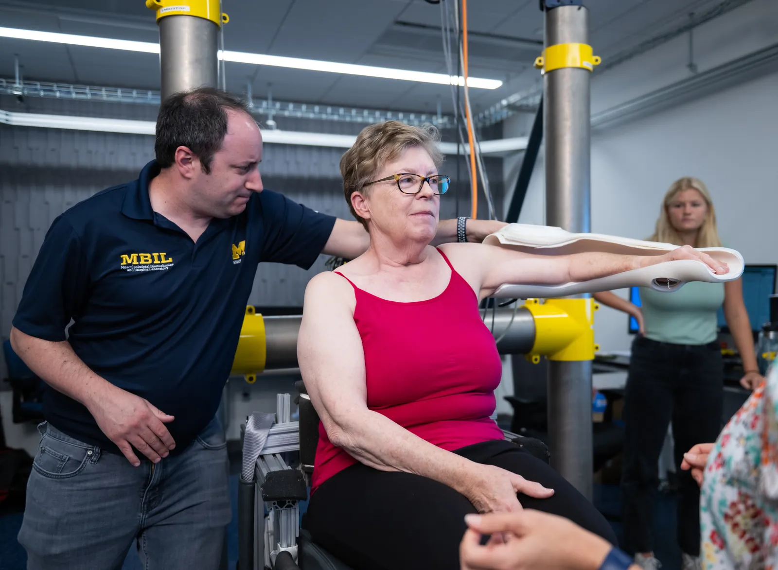A researcher guides a participant through a shoulder range-of-motion assessment in the MBIL laboratory.